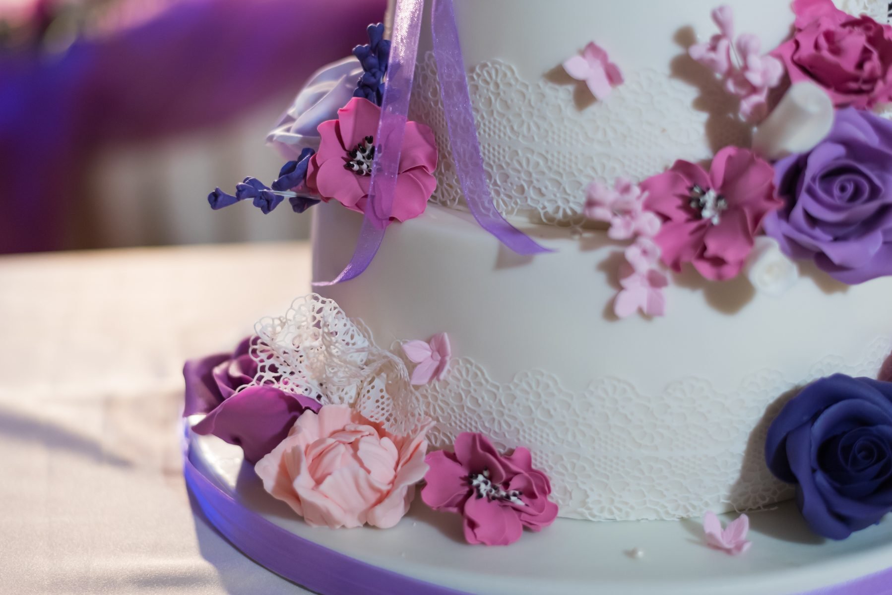 美丽的翻糖覆盖的蛋糕装饰可食用的花边和一束紫色的花