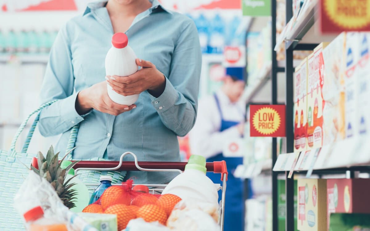 女人在超市购物，阅读食品标签，营养和质量概念