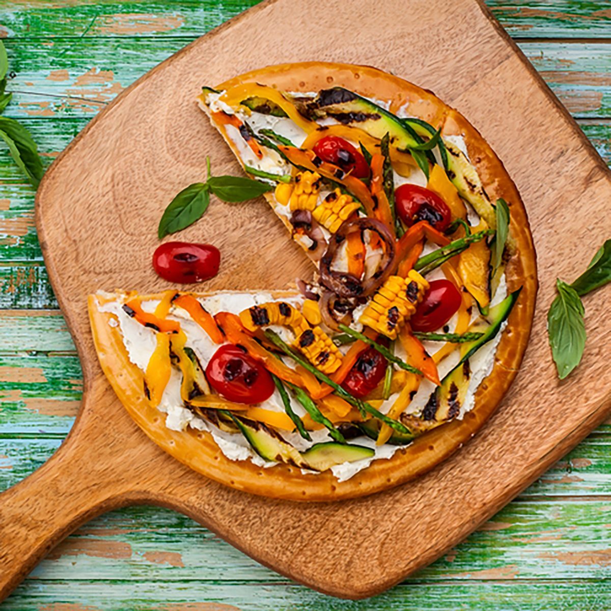 美味的夏日开胃菜:素食披萨配烤蔬菜和软奶酪放在木板上。俯视图