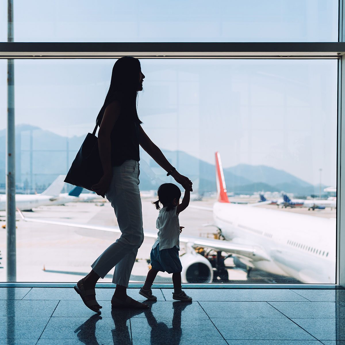 轮廓的快乐年轻可爱的小女儿亚洲妈妈手牵手看通过窗口在机场等待飞机起飞用途可重复使用的袋子
